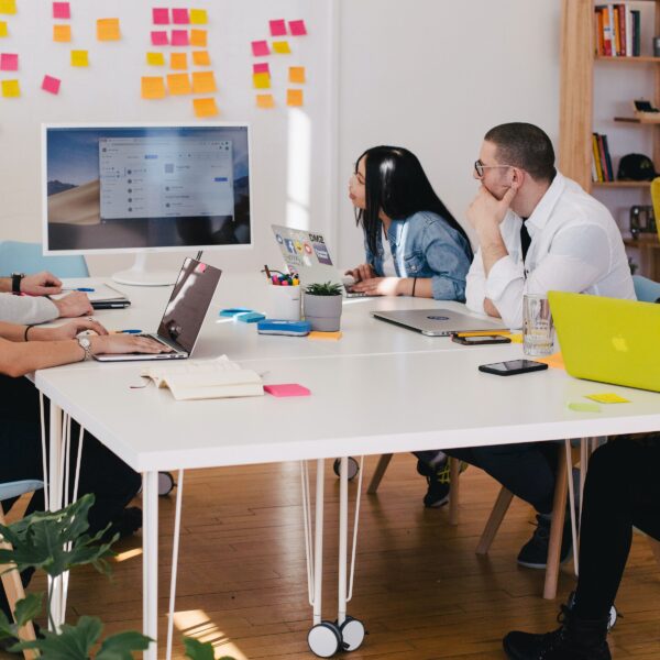 Group of educators sitting around table and looking at a screen surrounded by post-it notes