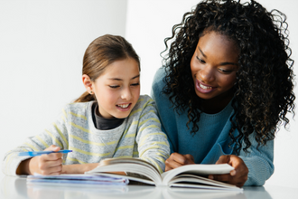 Woman tutor with student at a table.