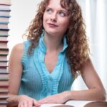 Woman sitting at desk staring at stack of instructional materials stacked on her desk