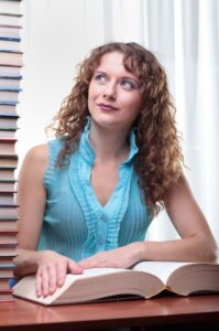 Woman sitting at desk staring at stack of instructional materials stacked on her desk